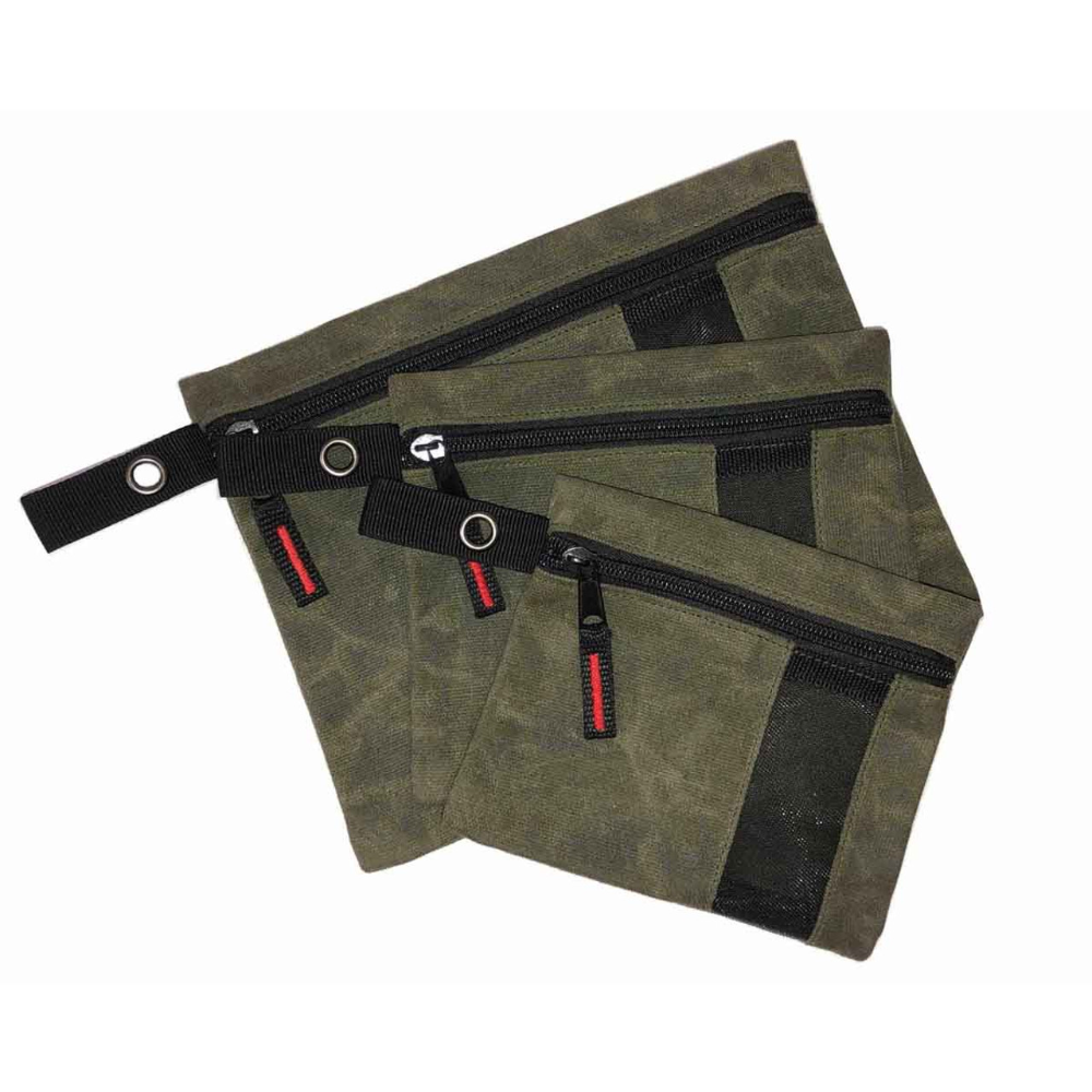 Set of three waxed canvas storage bags with leather handles and brass hardware on outdoor gear
