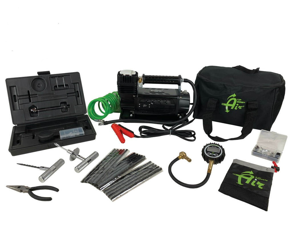 Overland Vehicle Systems portable air compressor system with tire deflator and 53-piece repair kit laid out on rugged surface