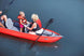 Two people in a red kayak on calm water with a paddle.
