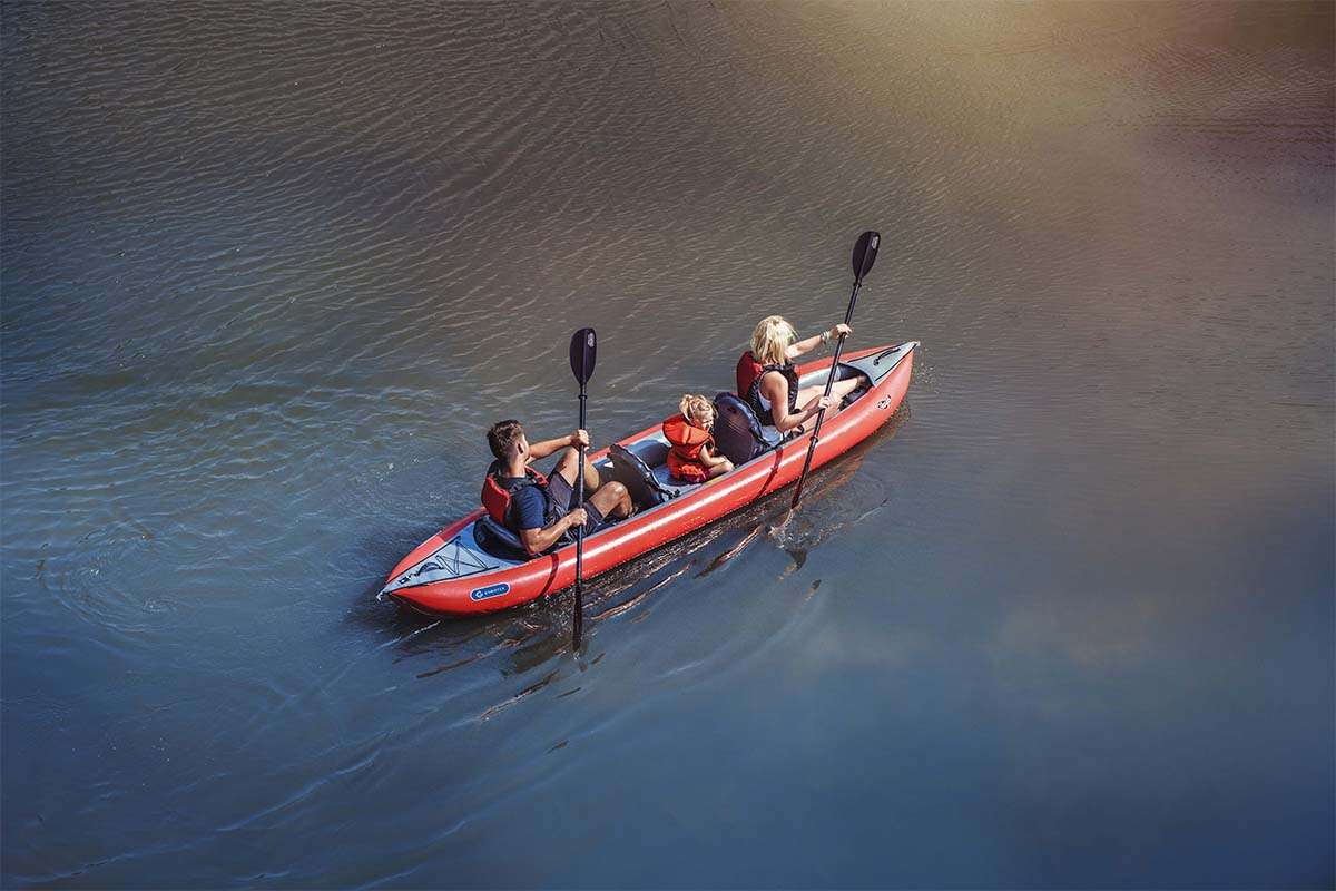 Two people in a red kayak on a calm body of water.