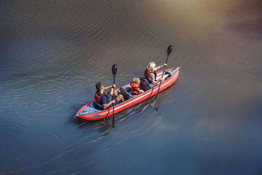 Two people in a red kayak on a calm body of water.